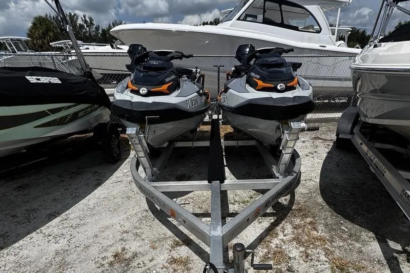 Slide: The Image of 2023 Sea-Doo FishPro Trophy jet skis on a trailer, parked near boats. - 5