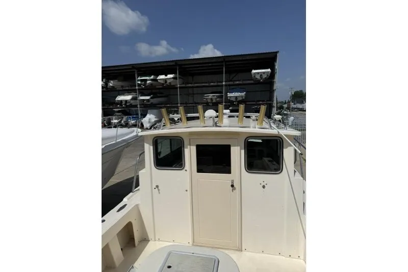 Slide: The Image of 2006 Parker 2520 SL Sport Cabin boat docked, showcasing cabin and rod holders. - 9