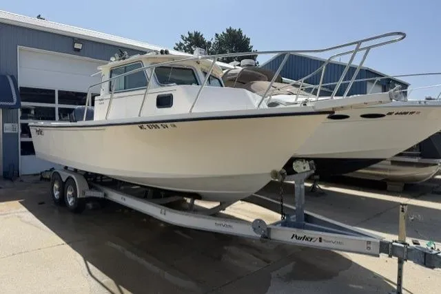 The Image of 2006 Parker 2520 SL Sport Cabin boat on trailer outside a garage. - 1