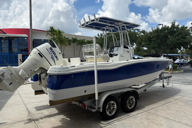 Slide: The Image of 2015 NauticStar 231 Coastal boat with Suzuki engine on a trailer, parked outdoors. - 4