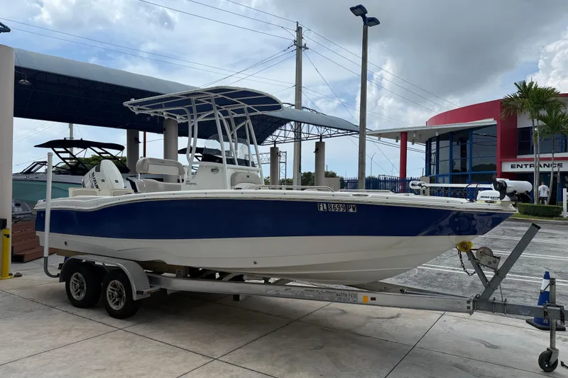 Slide: The Image of 2015 NauticStar 231 Coastal boat on trailer at dealership, blue and white design. - 3