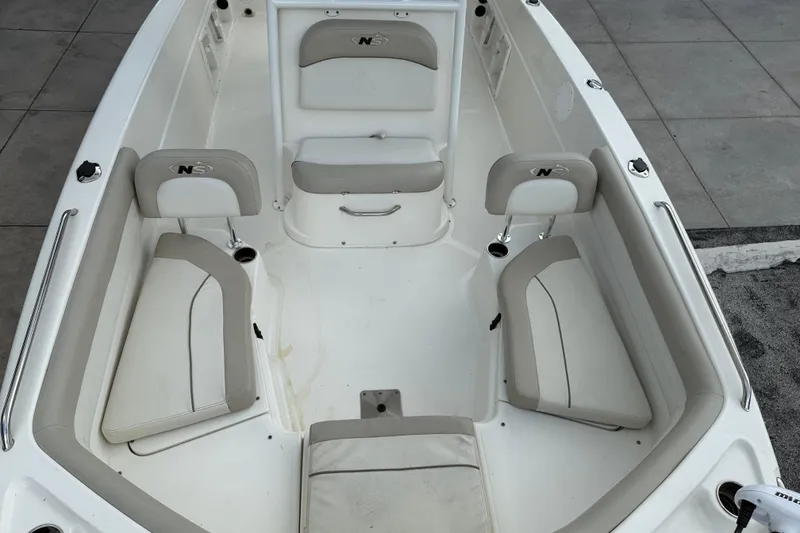 Slide: The Image of 2015 NauticStar 231 Coastal boat interior with cushioned seating and storage compartments. - 14