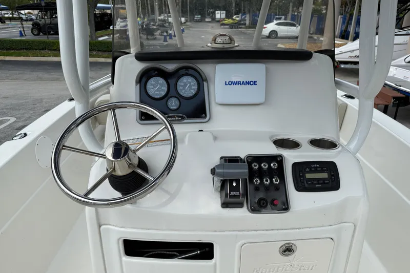 Slide: The Image of 2015 NauticStar 231 Coastal boat dashboard with steering wheel and navigation instruments. - 12