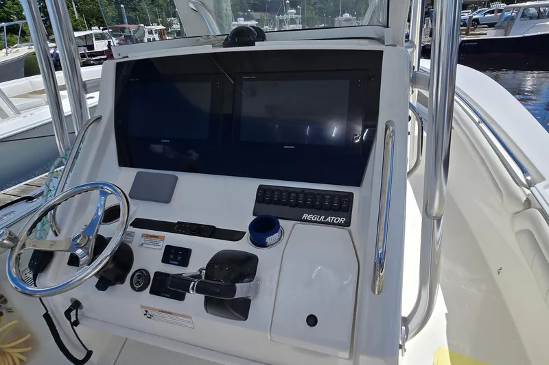 Slide: The Image of 2018 Regulator 28 Forward Seating boat dashboard with dual Garmin displays and steering wheel. - 22