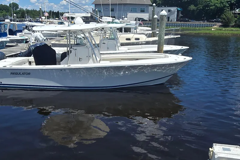 Slide: The Image of 2018 Regulator 28 Forward Seating boat docked in a marina under clear skies. - 1