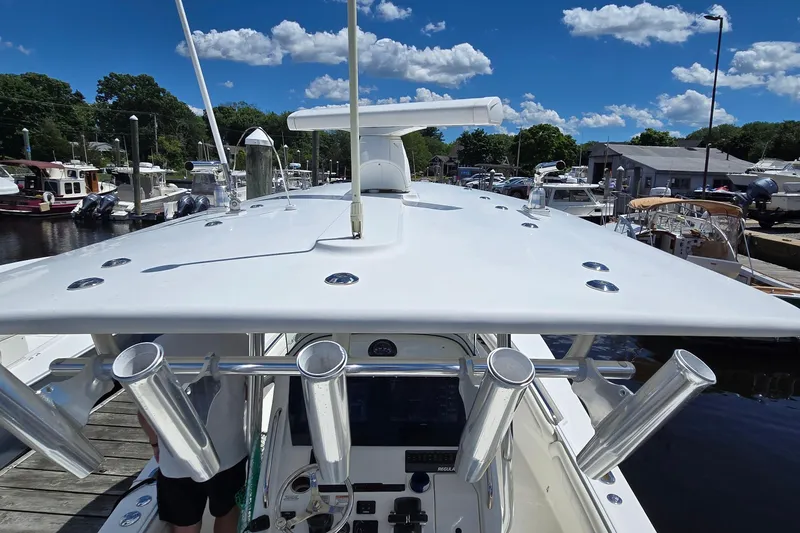 Slide: The Image of 2018 Regulator 28 Forward Seating boat docked, showcasing sleek design and rod holders under a clear sky. - 34