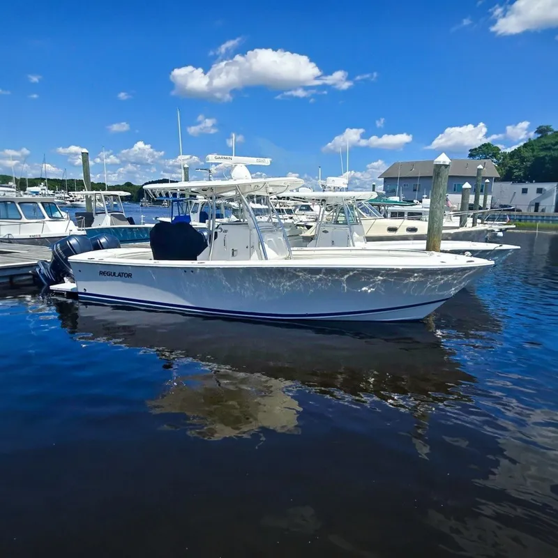 The Image of A white boat docked with a clear sky and other boats in the background. - 0