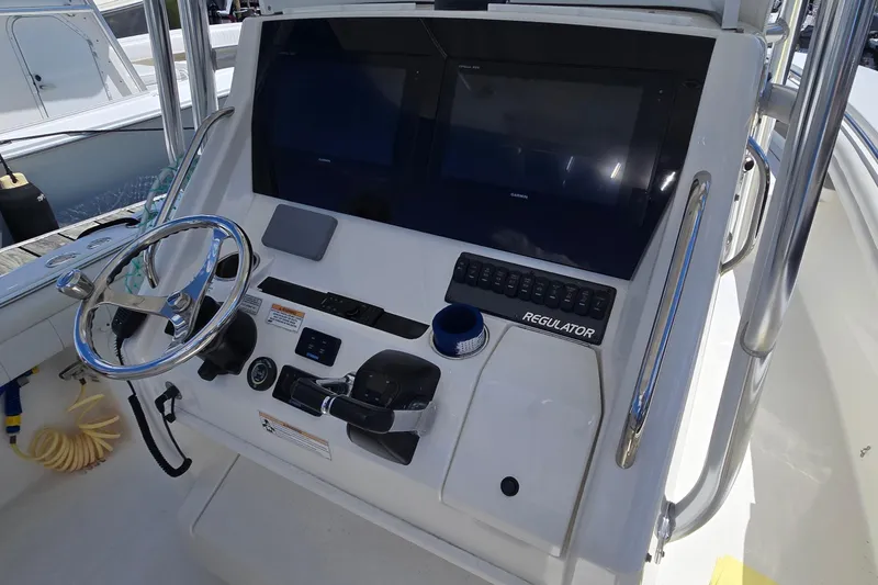 Slide: The Image of 2018 Regulator 28 Forward Seating boat dashboard with steering wheel and navigation controls. - 23