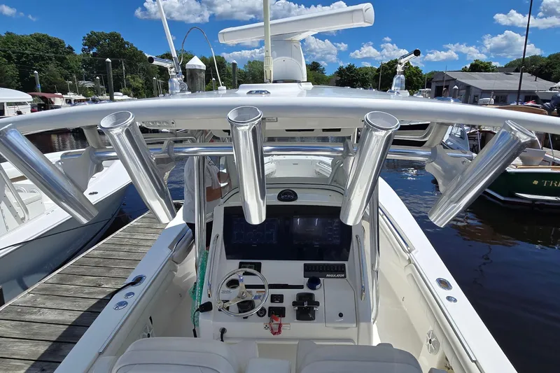 Slide: The Image of 2018 Regulator 28 Forward Seating boat with rod holders and helm, docked under blue sky. - 35