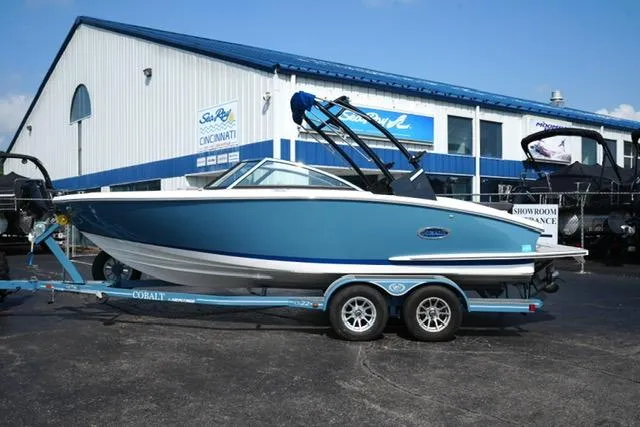 The Image of 2024 Cobalt CS22 boat on trailer outside dealership, blue and white exterior. - 1