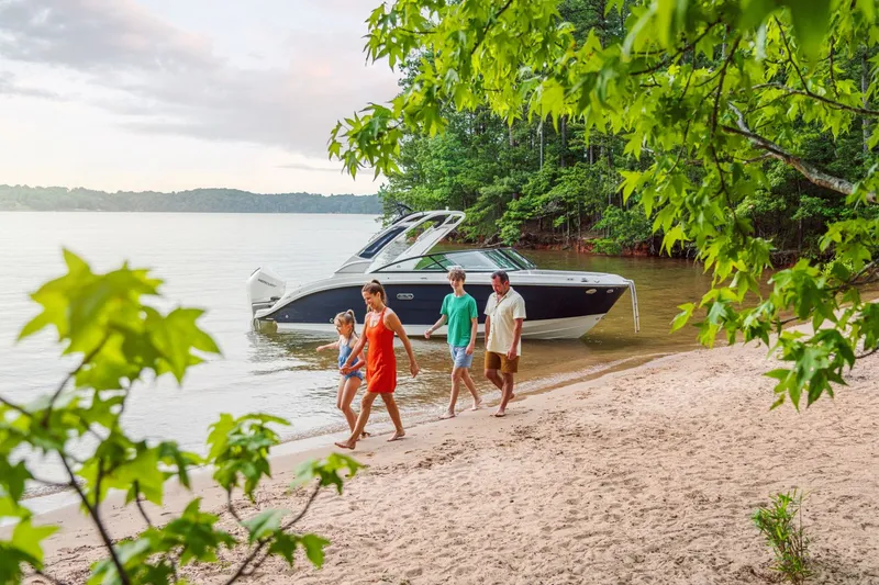 Slide: The Image of A Sea Ray SDX 250 Outboard is docked by a tranquil lake shore, surrounded by trees. - 33