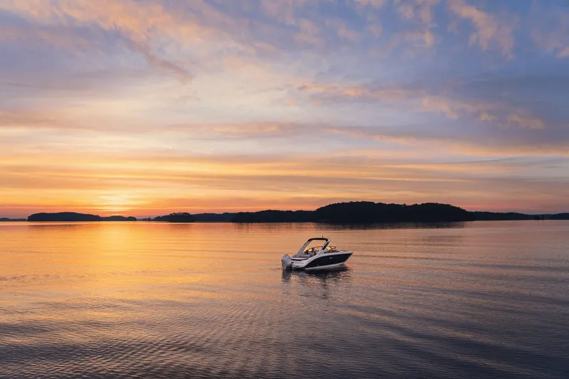 Slide: The Image of A Sea Ray SDX 250 Outboard boat on calm water at sunset, surrounded by islands. - 42