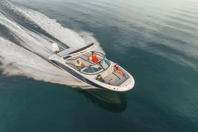 Slide: The Image of A 2026 Sea Ray SDX 250 Outboard speeds across calm water with three people on board. - 2