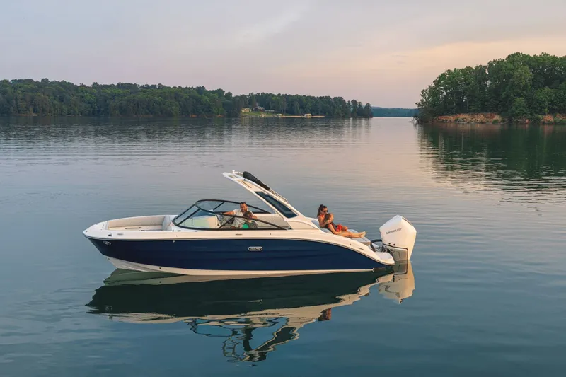 Slide: The Image of A sleek blue and white boat floating calmly on a serene lake, surrounded by trees. - 29