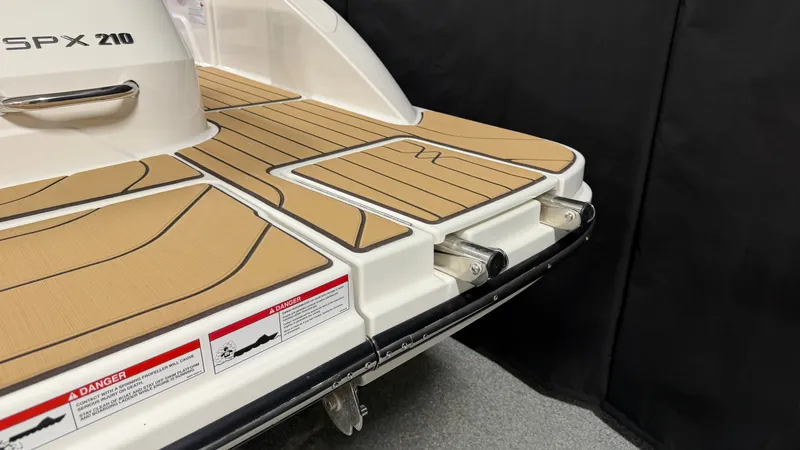Slide: The Image of The image shows the stern of a Sea Ray SPX 210 boat with teak-style decking and safety labels. - 11