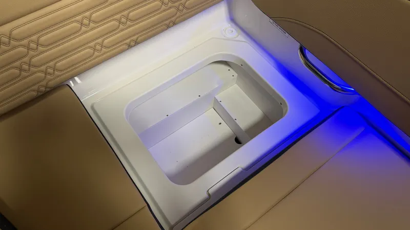 Slide: The Image of An illuminated storage compartment on a Sea Ray SPX 210 boat, surrounded by cushioned seating. - 30