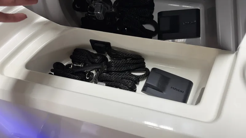Slide: The Image of A storage compartment on a Sea Ray SPX 210 boat with black ropes and a Fusion device. - 45