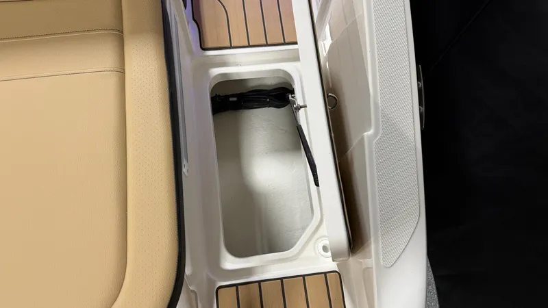 Slide: The Image of An open storage compartment on a Sea Ray SPX 210 boat with wood flooring and beige seating. - 16