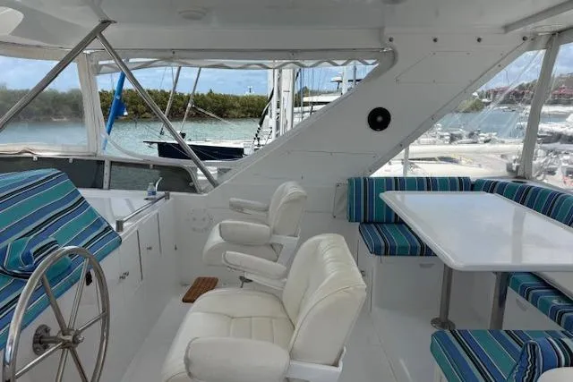 Slide: The Image of Interior of 2000 Ocean Alexander 60 Trawler with white seating and striped cushions. - 8