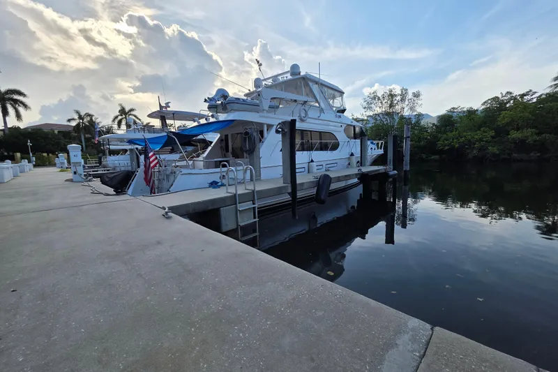 The Image of Ocean Alexander 60 Trawler 2000 docked by a serene waterfront with palm trees. - 0