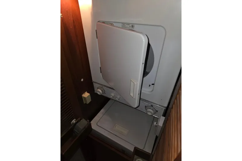 Slide: The Image of Laundry area inside 2000 Ocean Alexander 60 Trawler yacht, featuring a compact washer and dryer. - 21