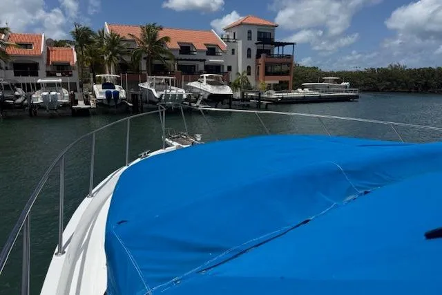 Slide: The Image of Ocean Alexander 60 Trawler, 2000 model, docked near waterfront homes and boats under a blue sky. - 3