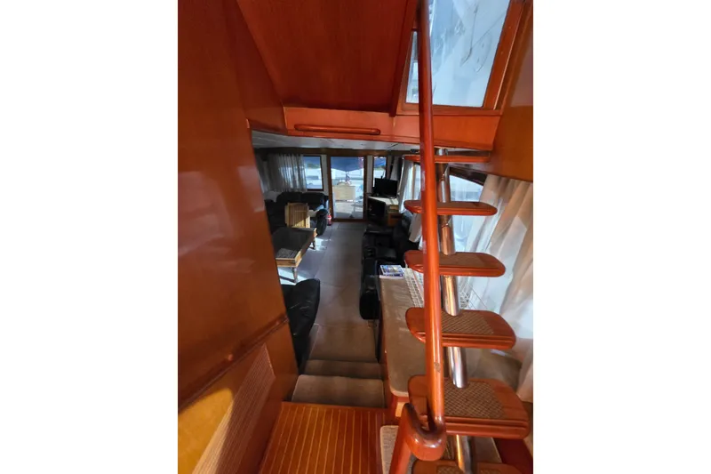 Slide: The Image of Interior view of 2000 Ocean Alexander 60 Trawler, featuring wooden stairs and cozy living area. - 13
