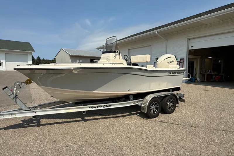 Slide: The Image of 2025 Grady-White Fisherman 180 boat on trailer, parked outside a garage. - 1