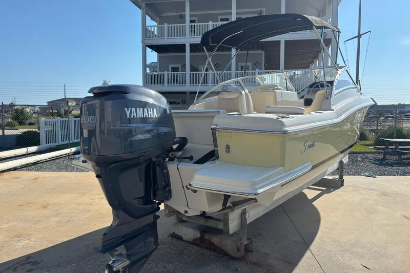 Slide: The Image of 2004 Scout 222 Dorado boat with Yamaha engine, docked near a coastal home. - 4