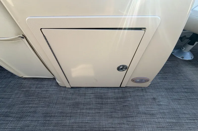 Slide: The Image of 2018 Sylvan Mirage 820 Cruise storage compartment with beige panel and lock. - 23
