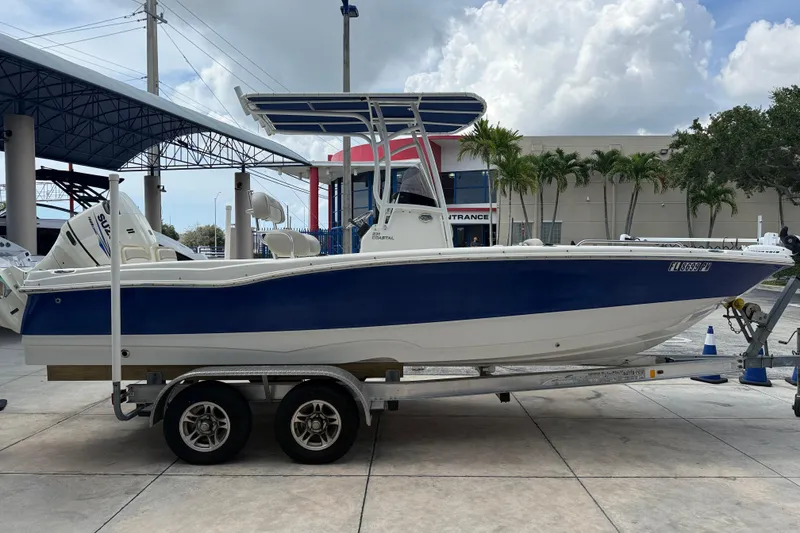 The Image of 2015 NauticStar 231 Coastal boat on trailer, blue and white design, parked outdoors. - 0