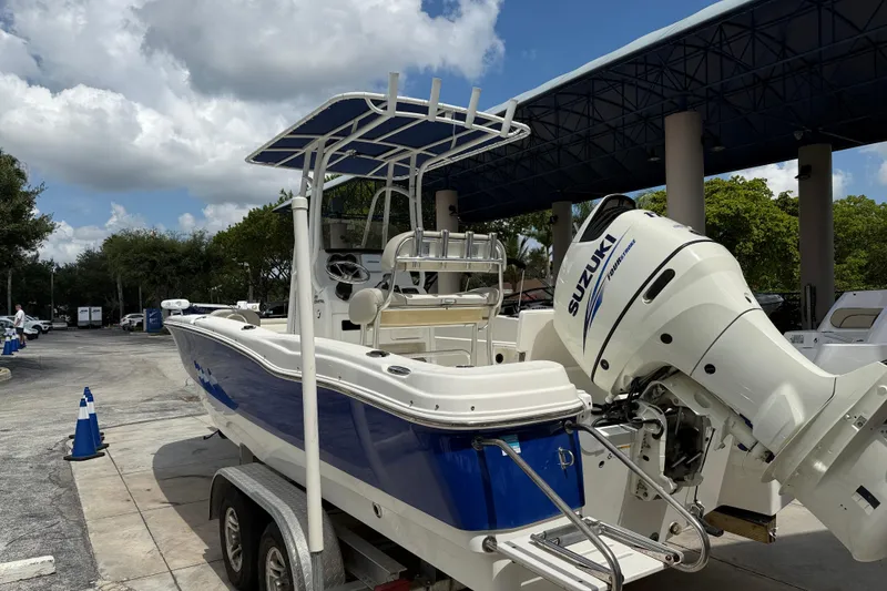 Slide: The Image of 2015 NauticStar 231 Coastal boat with Suzuki engine on trailer, parked outdoors. - 6