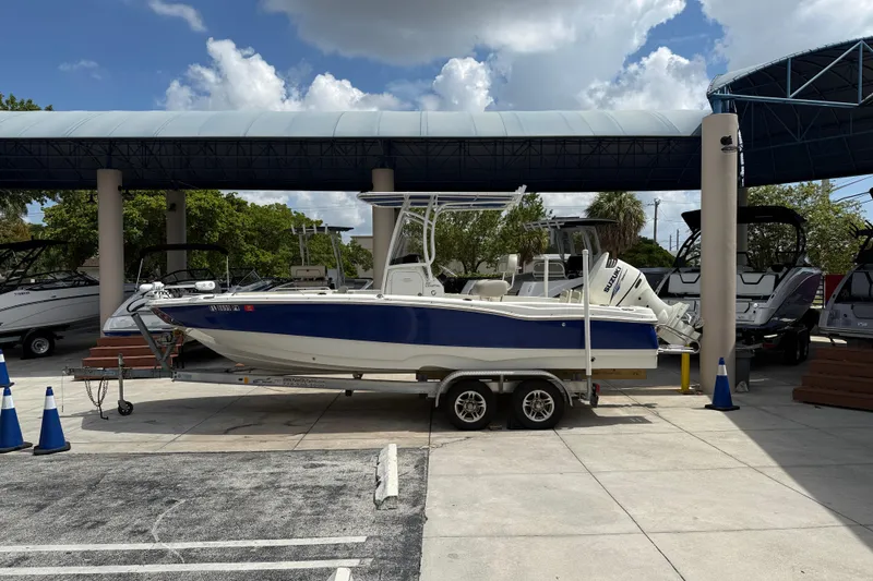 Slide: The Image of 2015 NauticStar 231 Coastal boat on trailer under canopy, surrounded by other boats. - 1