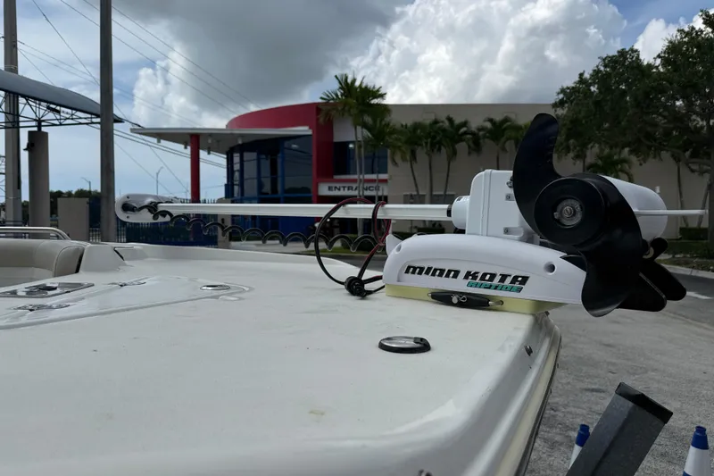 Slide: The Image of 2015 NauticStar 231 Coastal boat with Minn Kota trolling motor, parked near a modern building. - 8