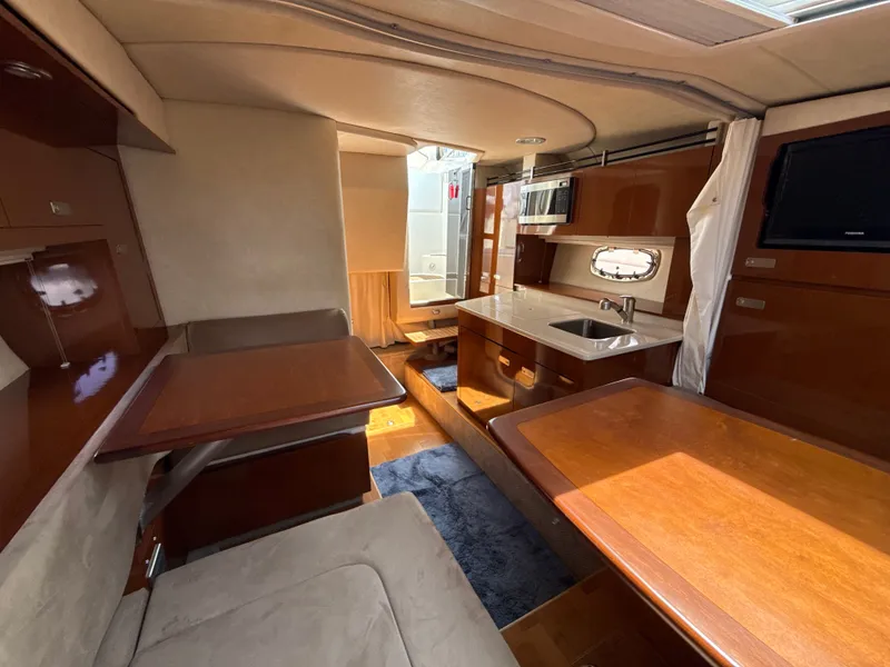 Slide: The Image of Interior of a 2010 Sea Ray Sundancer 310 with wooden tables and a kitchenette. - 33