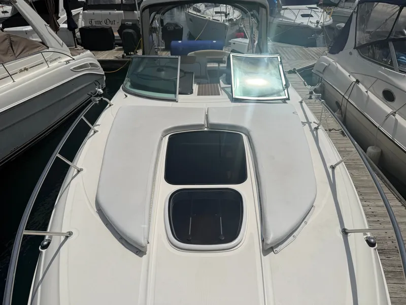 Slide: The Image of A 2010 Sea Ray Sundancer 310 docked at a marina. It features a spacious foredeck with two windows. - 6