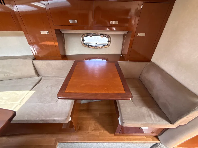 Slide: The Image of The interior of a 2010 Sea Ray Sundancer 310 features a cozy seating area with a wooden table. - 31