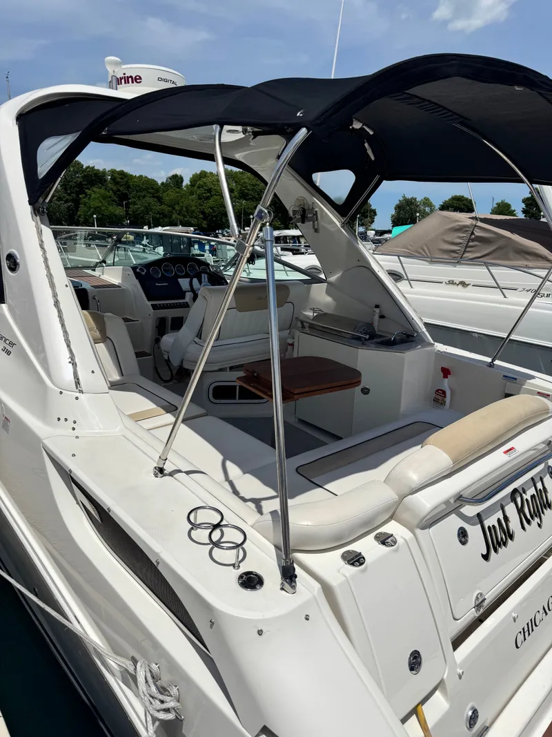 Slide: The Image of A 2010 Sea Ray Sundancer 310 with an open cockpit and black sunshade, docked in a marina. - 4