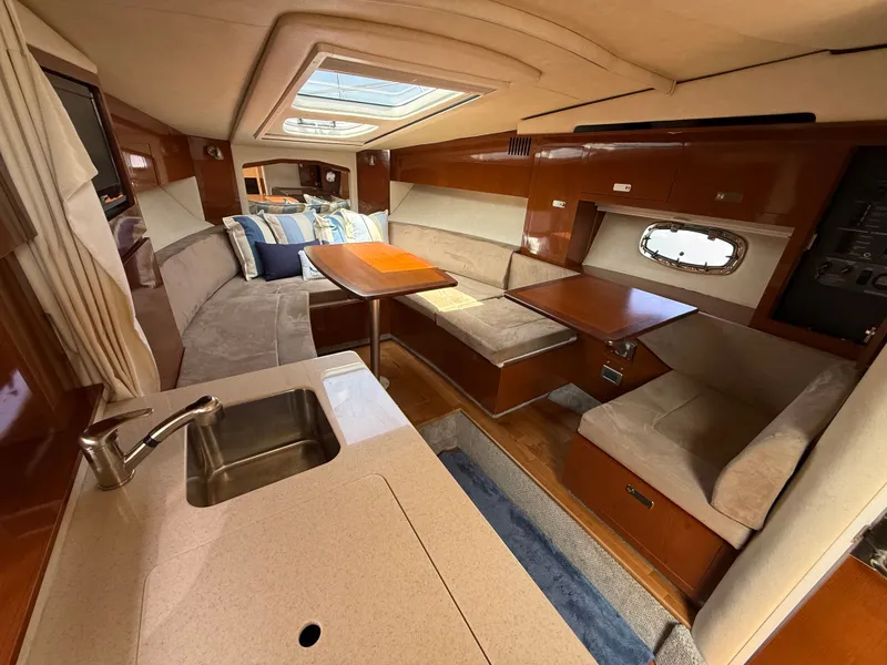 Slide: The Image of Interior of a 2010 Sea Ray Sundancer 310 with cozy seating areas and a small table. - 27