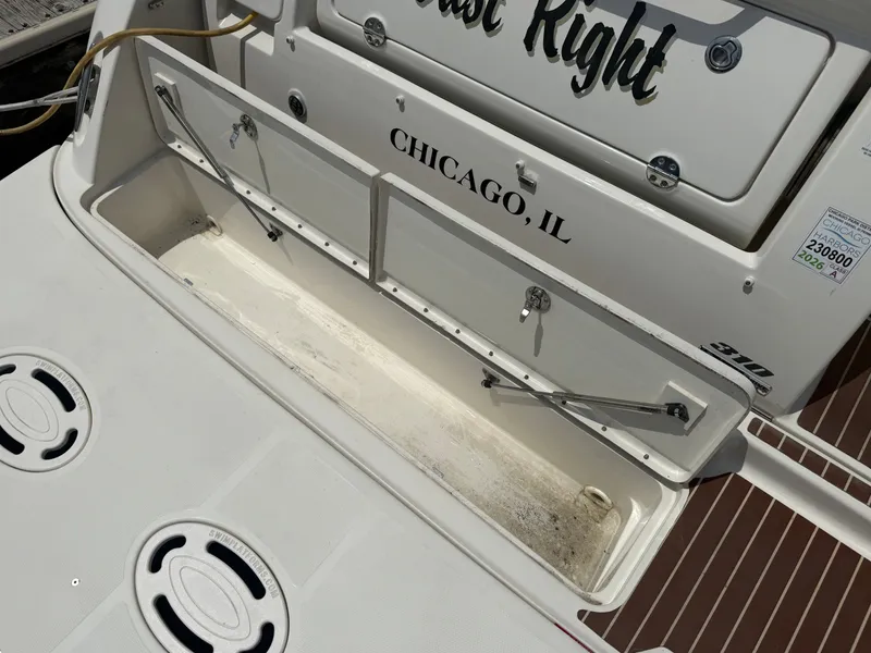 Slide: The Image of The image shows the stern of a 2010 Sea Ray Sundancer 310 boat registered in Chicago, IL. There is an open storage compartment with hydraulic arms. - 47