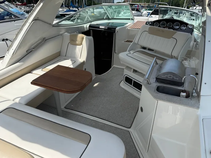 Slide: The Image of The image shows the cockpit of a 2010 Sea Ray Sundancer 310 with beige seating and a wooden table. - 11