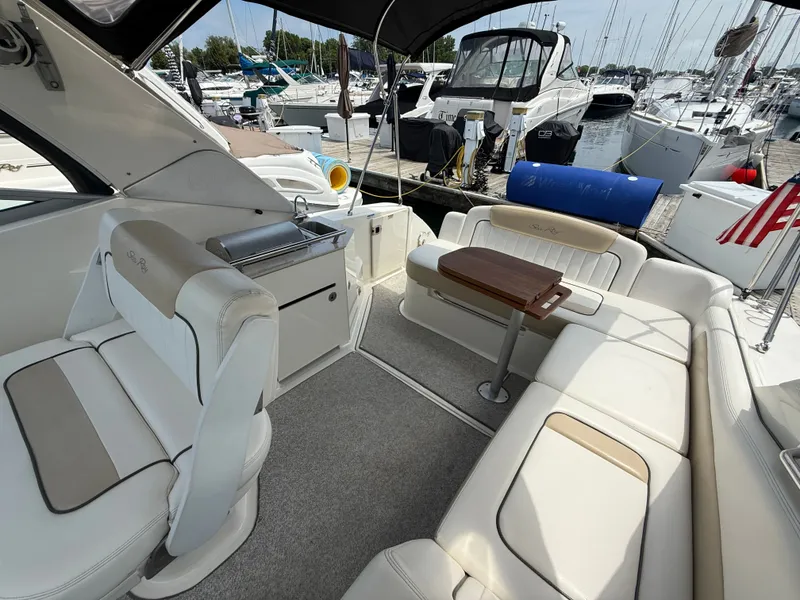 Slide: The Image of The image shows the cockpit of a 2010 Sea Ray Sundancer 310 with beige seating and a wooden table. - 9