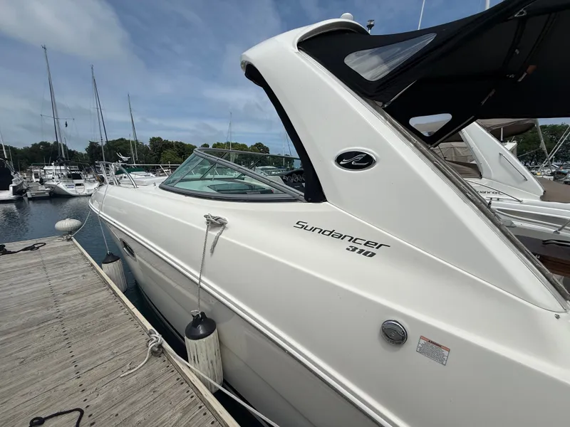 Slide: The Image of A 2010 Sea Ray Sundancer 310 docked. It features a sleek, white design. - 2