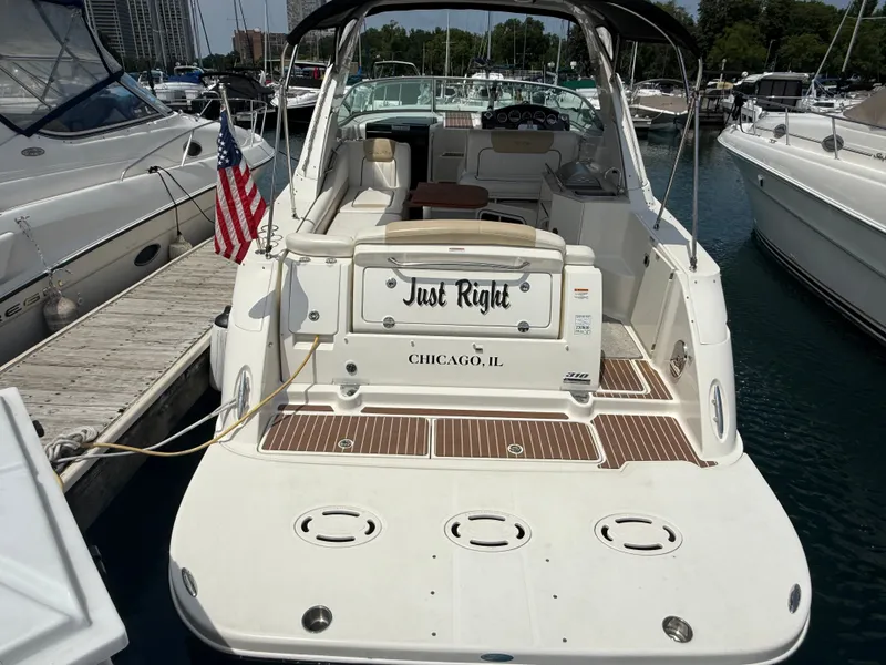 Slide: The Image of A 2010 Sea Ray Sundancer 310 docked. It features a spacious cockpit and an American flag. - 4