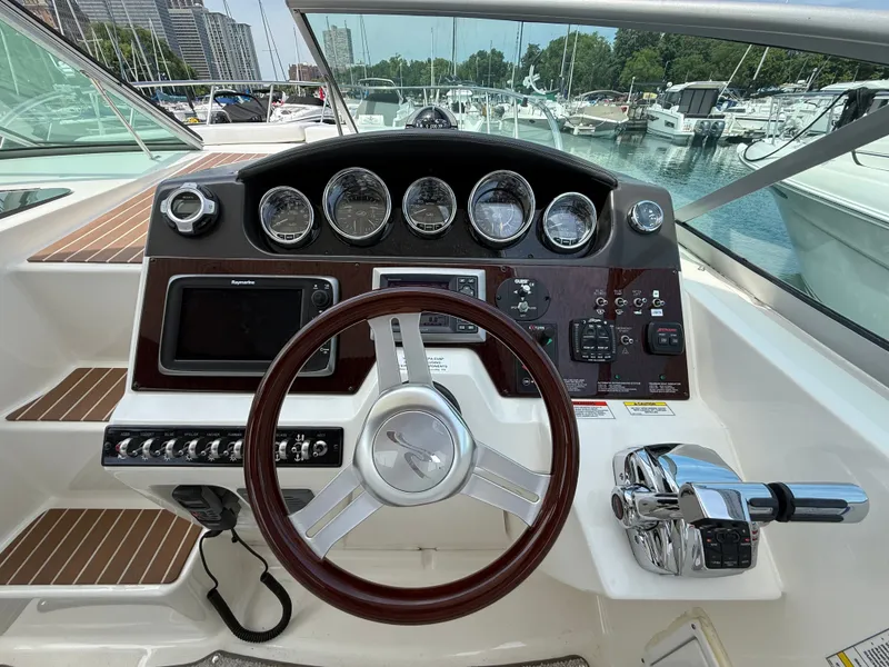 Slide: The Image of The 2010 Sea Ray Sundancer 310 cockpit features an elegant dashboard with wood paneling. - 22