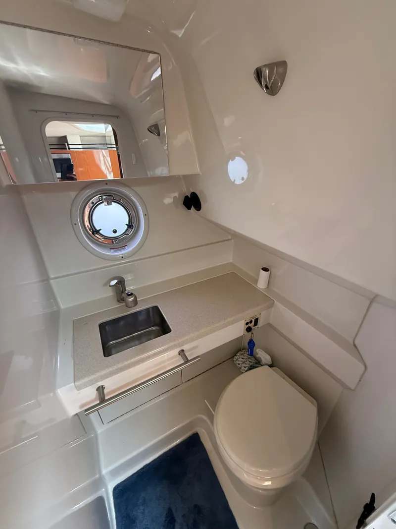 Slide: The Image of The image shows a clean boat bathroom with a sink, toilet, and porthole. - 39