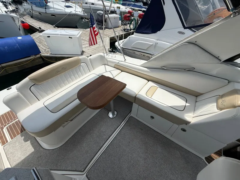 Slide: The Image of The image shows the cockpit of a 2010 Sea Ray Sundancer 310 with beige leather seating and a wooden table. - 14