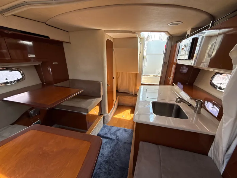 Slide: The Image of Interior of a 2010 Sea Ray Sundancer 310 with a kitchen, seating area, and wooden furnishings. - 32