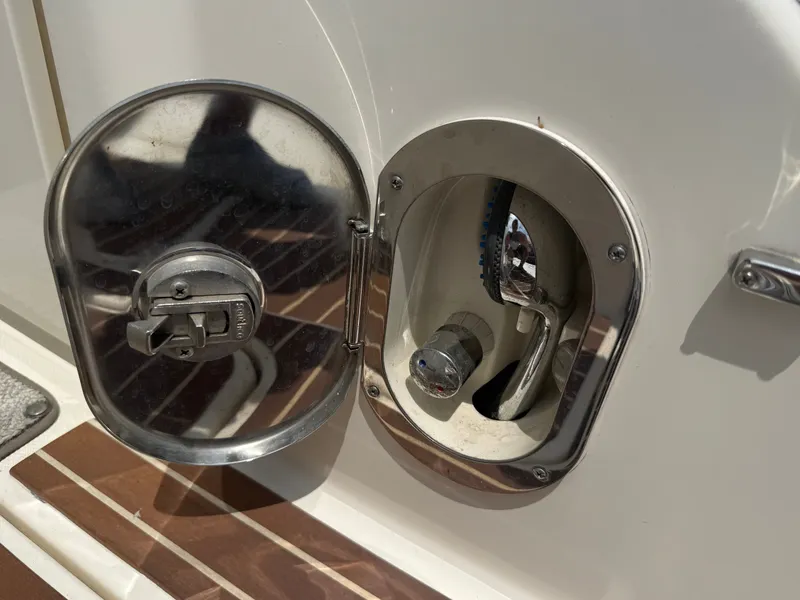 Slide: The Image of An open fuel cap on a boat with a metal latch and hose connection. - 48