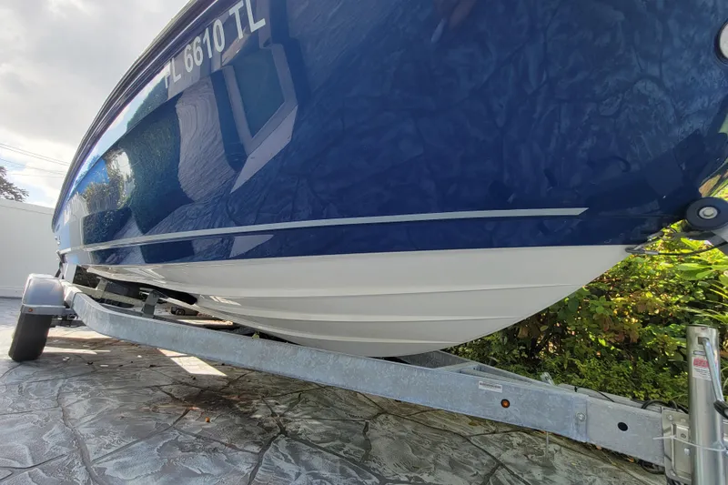 Slide: The Image of 2023 Bayliner VR6 Bowrider OB on trailer, blue hull, parked outdoors. - 4